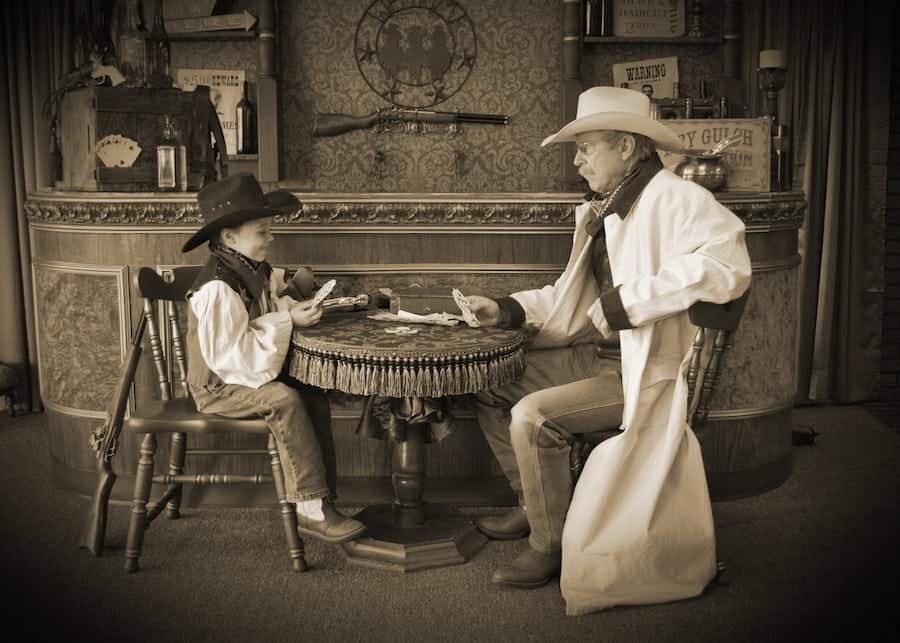 Little boy and man playing cards in a saloon