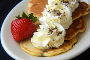 Chocolate chip pancakes with whipped cream and a strawberry.