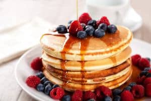 Pancakes covered in berries and maple syrup.