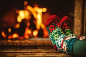 A pair of feet in wool socks in front of the fireplace.