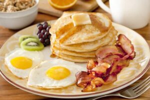 Pancakes, eggs, bacon, and fruit.