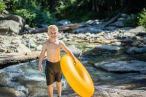 little boy at the river with a yellow tube