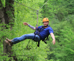A white man with tattoo is riding Wahoo Ziplines