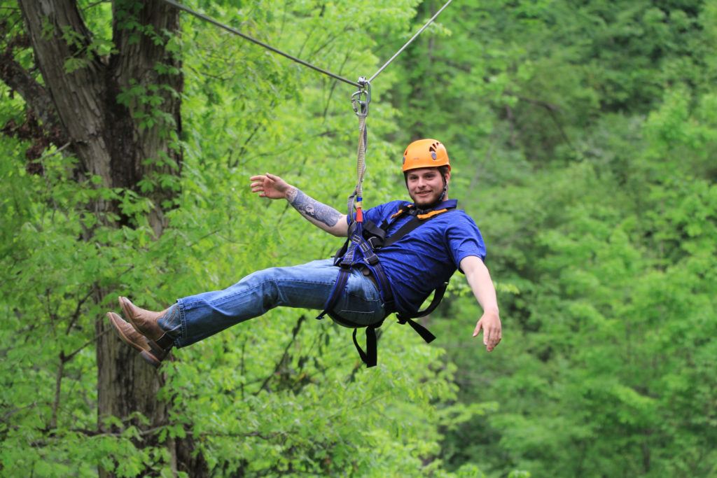 A white man with tattoo is riding Wahoo Ziplines