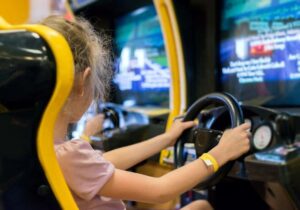 girl playing racing game in arcade
