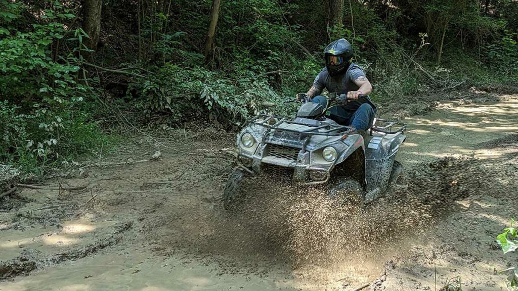 a person is riding ATV through the mud